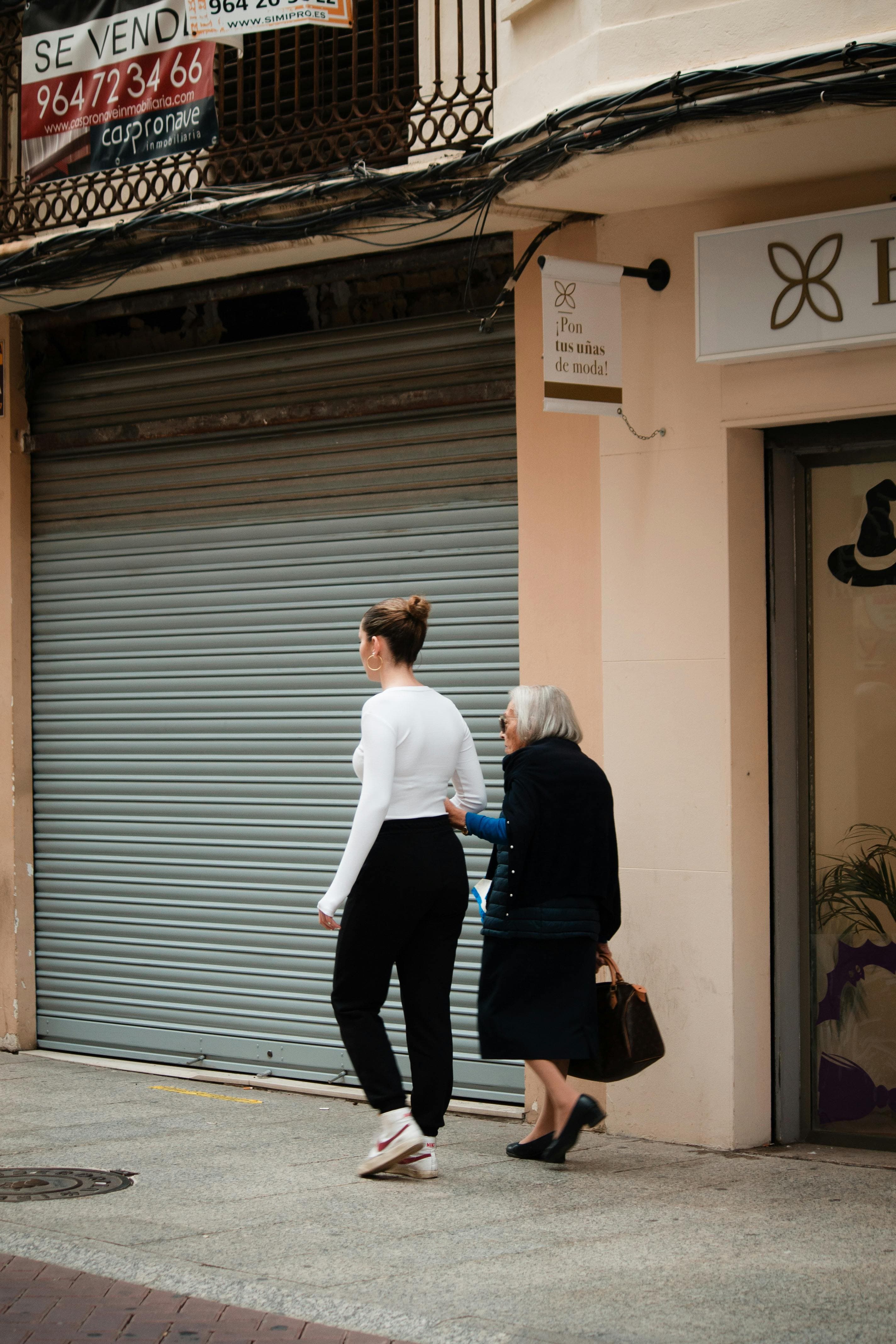 An adult daughter walking beside and supporting her mother